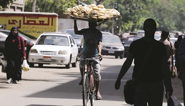 A bakery worker rides a bicycle as he carries fresh bread on his head in Cairo (file). The Egyptian president has repeatedly instructed officials to ensure that the poorest Egyptians arenu2019t affected by efforts to trim budget deficits. Authorities have been stockpiling key commodities, including fuel and sugar, to safeguard against possible price gouging. But discontent remains widespread.
