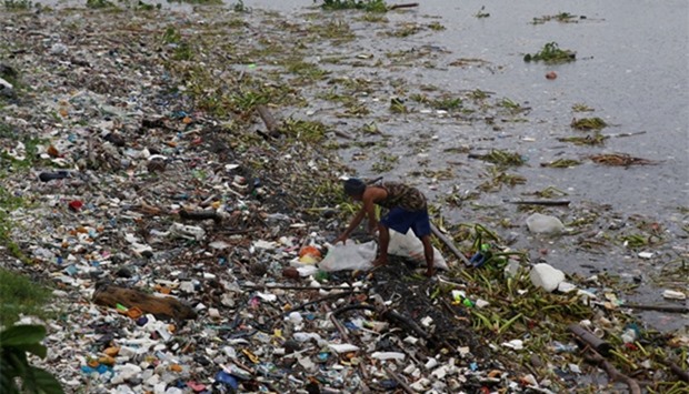 A resident collects recyclable materials from debris along the shore in Manila bay after Typhoon Sar