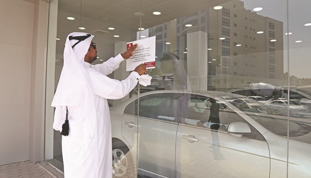 An official from the MEC pastes a notice about the closure of the car showroom.