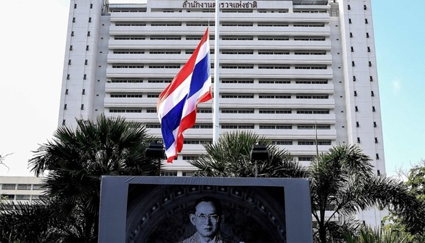 The Thai national flag flies at half mast in the backdrop of a portrait of late King Bhumibol