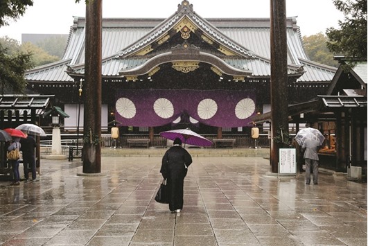 A visitor in a kimono bows at the Yasukuni Shrine in Tokyo.