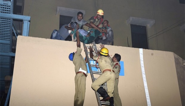 Indian rescue workers lowering a victim of the massive fire at SUM hospital building