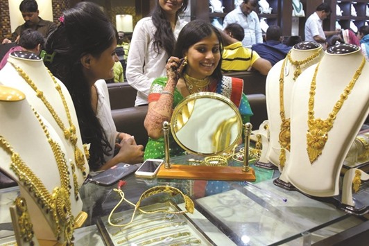 A woman tries out gold jewellery at a shop in Jaipur. A crackdown on black money and higher returns from other asset classes have hit the demand for gold.