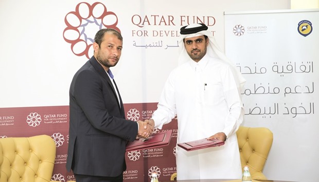 Officials exchange documents after signing the agreement.