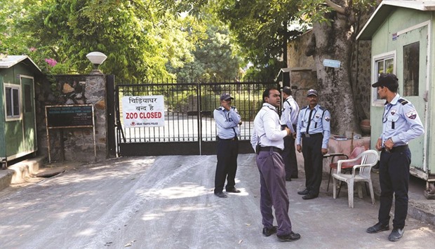 Private security guards stand near a banner placed at the main gate of the Delhi zoo which has temporarily closed after two birds died of bird flu.