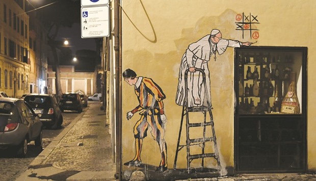 A street art mural by Italian artist Maupal of Pope Francis playing tic-tac-toe and drawing peace signs as a Swiss guard keep watches the street near the Vatican.
