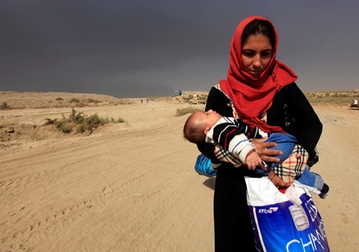A displaced woman who is fleeing from clashes holds her baby in Qayyarah, during an operation to attack Islamic State militants in Mosul, Iraq, yesterday.