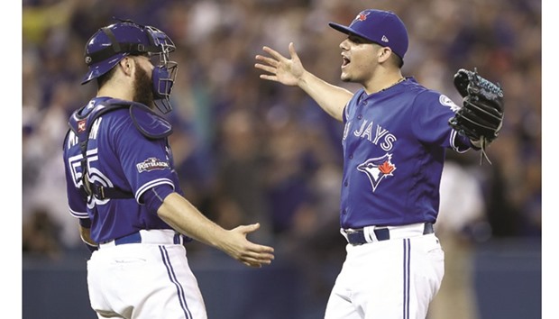 Roberto Osuna (right) and Russell Martin of the Toronto Blue Jays celebrate after defeating the Cleveland Indians with a score of 5 to 1 in game four of the American League Championship Series at Rogers Centre in Toronto. (AFP)