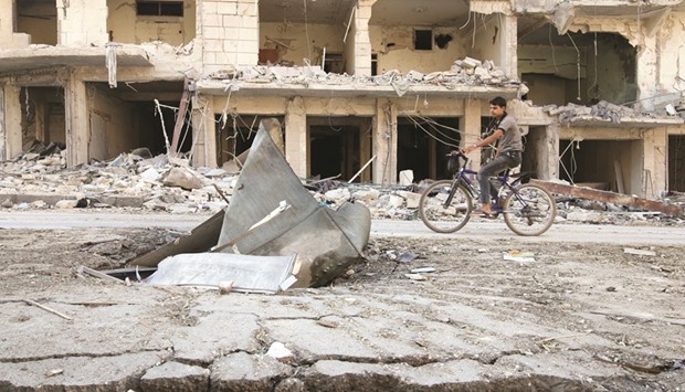 A man rides a bicycle near damaged ground in the rebel held besieged al-Sukkari neighbourhood of Aleppo, Syria yesterday.