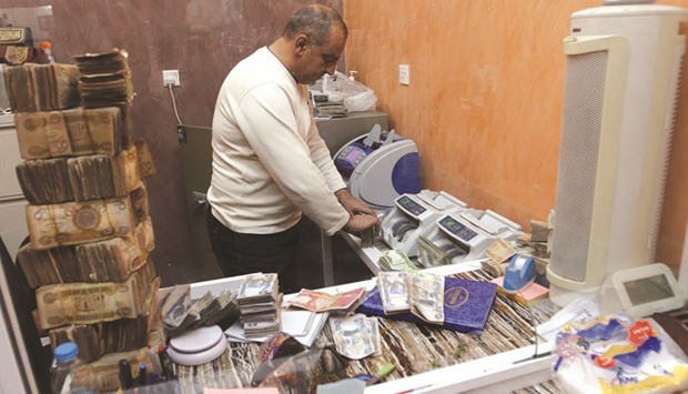 A man counts wads of Iraqi dinars on a machine at a currency exchange shop in Baghdad. Iraqu2019s plans to raise $2bn on international debt markets to help fill a budget gap caused by low oil prices were thwarted last week by the US Congressu2019 refusal to guarantee half the bondsu2019 value.
