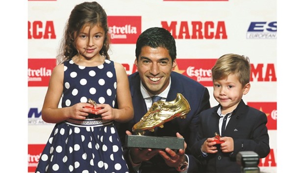 Barcelonau2019s striker Luis Suarez, his daughter Delfina and son Benjamin pose with his 2016 European Golden Shoe soccer trophy in Barcelona yesterday. (Reuters)