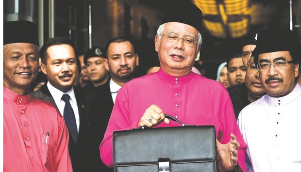 Malaysiau2019s Prime Minister Najib Razak poses with his briefcase as he leaves to unveil the 2017 financial budget to Parliament House, outside the finance ministry in Putrajaya yesterday.