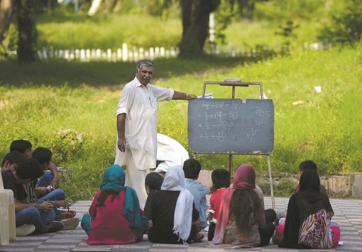Muhammad Ayub teaches pupils at a makeshift school in a park in Islamabad.