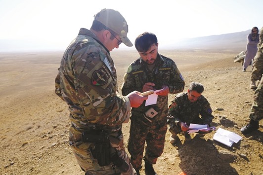 An American military adviser consults with an Afghan Tactical Air Controller during an exercise at a range outside Kabul.