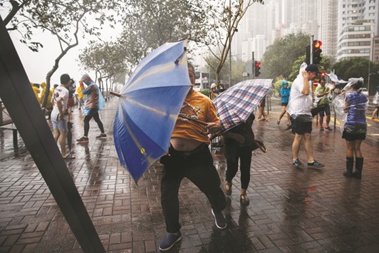 People use their umbrellas near a coastal barrier  in Hong Kong yesterday.