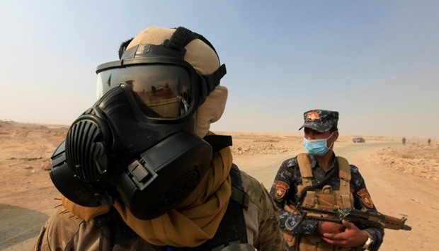 Iraqi forces wear protective masks after winds brought fumes from a nearby sulfur plant set alight by Islamic State militants, at south of Mosul in Qayyara, Iraq
