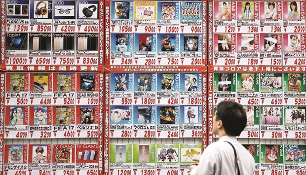 A man looks at price lists outside a store in Tokyo. Japanese five-year inflation swaps remain mired below 0.3%, resisting pressure from rising oil and commodity prices.