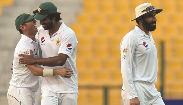 Pakistanu2019s Yasir Shah (left), and Rahat Ali (centre) celebrate next to captain Misbah-ul-Haq after the dismissal of West Indiesu2019 Kraigg Brathwaite (unseen) on the second day of the second Test at the Sheikh Zayed Stadium in Abu Dhabi yesterday. (AFP)