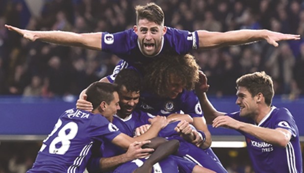 Chelseau2019s defender Gary Cahill (top) jumps onto the huddle to join the celebration after midfielder Nu2019Golo Kante scored their fourth goal during the English Premier League football match against Manchester United at Stamford Bridge in London yesterday. (AFP)