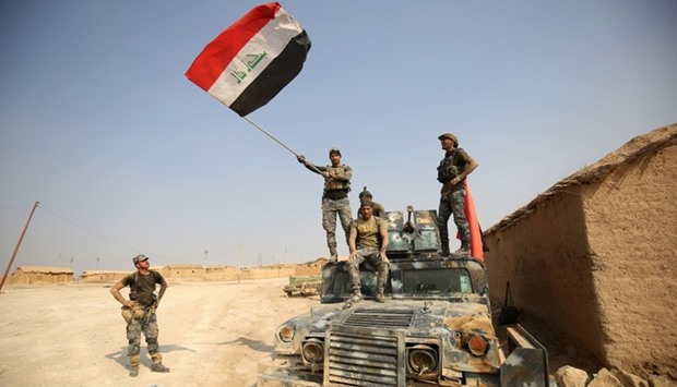 Iraqi government forces raise their national flag as they enter the village of al-Khuwayn, south of Mosul, after recapturing it from Islamic State (IS) group jihadists on October 23, 2016, in part of an ongoing operation to tighten the noose around Mosul and reclaim the last major Iraqi city under IS control.