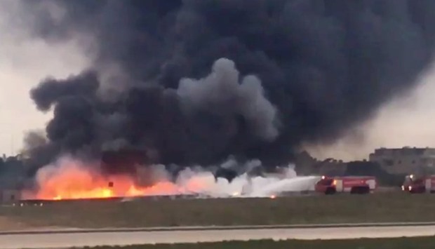Still image taken from video shows fire trucks aiming their hoses at the burning wreckage of a small plane which crashed at the edge of the runway at the airport in Valletta,