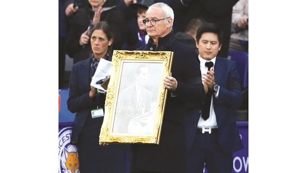 Leicester City manager Claudio Ranieri holds up a photograph in memory of the late Thai King Bhumibol Adulyadej before their EPL match against Crystal Palace on Saturday. (Reuters)