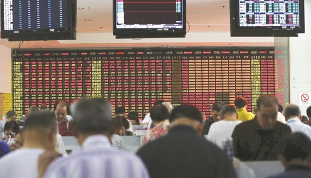 Investors look at computer screens in front of an electronic board showing stock information at a brokerage house in Shanghai. The Composite closed up 1.2% to 3,128.25 points yesterday.