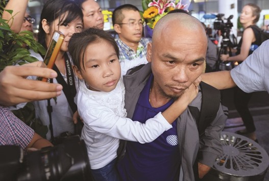 Nguyen Van Xuan (R), 35, one of three Vietnamese sailors freed by Somali pirates, holds his daughter at Hanoiu2019s international airport Noi Bai on October 25, 2016.