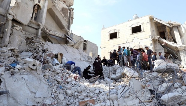 Civil defense members and civilians search for survivors under the rubble of a site hit by overnight airstrikes in the town of Kafr Takharim, in Idlib Governorate, Syria October 24