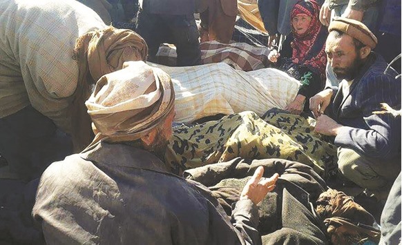 Afghan men and a woman gather around the bodies of civilians, including children, who were allegedly killed by Islamic State (IS) militants in Ghor province yesterday.