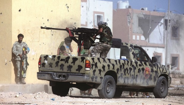 A member of Libyan forces allied with the UN-backed government fires a weapon on a pickup truck during a battle with Islamic State militants in Giza Bahreya, in Sirte.