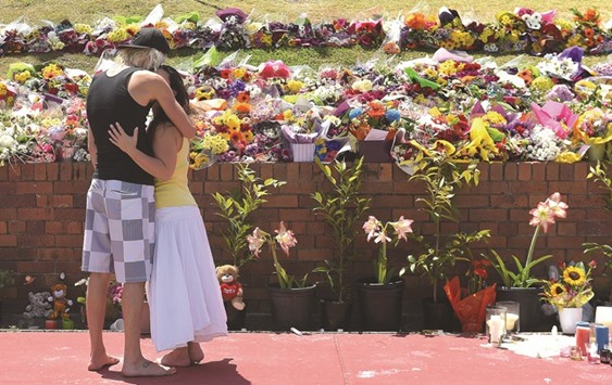 Mourners leave floral tributes outside the main entrance to Dreamworld on the Gold Coast.