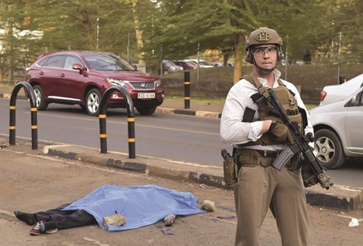 A US security officer stands guard near the body of a man after he was shot and killed by Kenyan police outside the US embassy in Nairobi.
