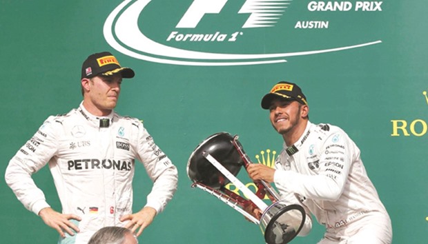 Mercedes driver Lewis Hamilton raises his victory trophy as teammate Nico Rosberg (left) looks on on the podium for the United States Grand Prix on Sunday. (Reuters)