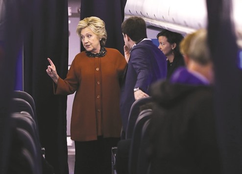 Clinton talks with members of her staff yesterday aboard her campaign plane at Westchester County Airport in White Plains, New York. With less than two weeks to go before the election, Clinton is campaigning in North Carolina with First Lady Michelle Obama.