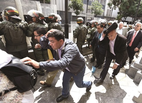 Opposition lawmakers protect themselves while they try to reach the National Assembly in Caracas yesterday.
