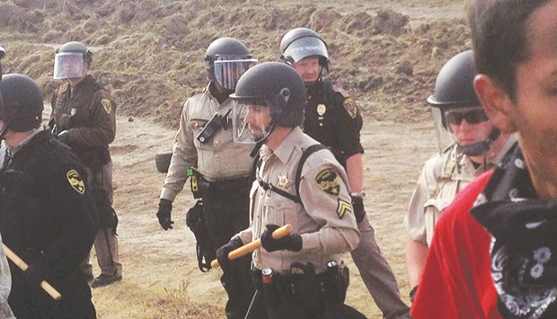 A line of police move towards a roadblock and encampment of Native American and environmental protesters near an oil pipeline construction site, near the town of Cannon Ball, North Dakota.