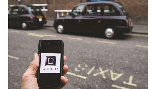 A photo illustration shows the Uber app logo displayed on a mobile telephone, as it is held up for a posed photograph in central London,