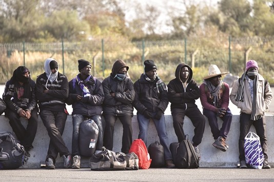 Migrants in Calais wait yesterday to board a bus leaving for a reception centre following a massive operation to clear the u2018Jungleu2019 migrant camp. Dozens of migrant youths stranded for two days in the Jungle as it was being demolished were offered transfers out of the camp yesterday.