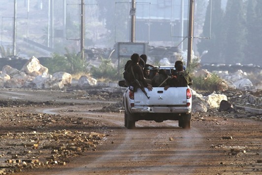Rebel fighters ride a vehicle after they took control of Dahiyet al-Assad, west Aleppo, yesterday.