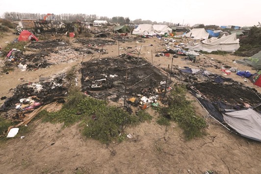 Debris of burned makeshift shelters are seen in the Calais u2018Jungleu2019 migrant camp yesterday during an operation to clear the squalid settlement. Work started again yesterday to tear down the remaining makeshift shelters. Mechanical diggers and other machines tore the structures in the camp, which was ravaged by fires after authorities moved in to clear the settlement.