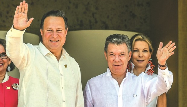 Panamau2019s President Juan Carlos Varela and Colombian President Juan Manuel Santos wave as Colombian first lady Maria Clemencia Rodriguez looks on during a welcome ceremony during the XXV Ibero-American Summit in Cartagena, Colombia.