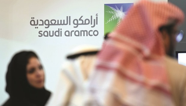 Saudi and foreign investors stand in front of the logo of Saudi state oil giant Aramco during the 10th Global Competitiveness Forum on January 25, 2016 in Riyadh. Saudi Arabia is unlikely to agree to an Opec deal that forces it to shoulder too much of the burden and lets Iran u201coff the hooku201d when the group meets to finalise production cuts at the end of next month, according to a report by the Oxford Institute for Energy Studies.