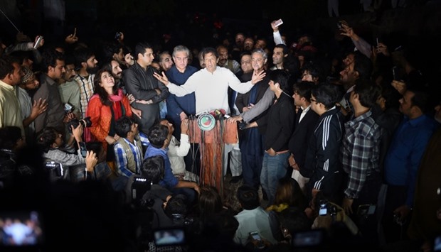 Pakistani opposition leader of the Tehreek-i-Insaf (PTI) political party Imran Khan (C) speaks during a press briefing outside his house in Islamabad