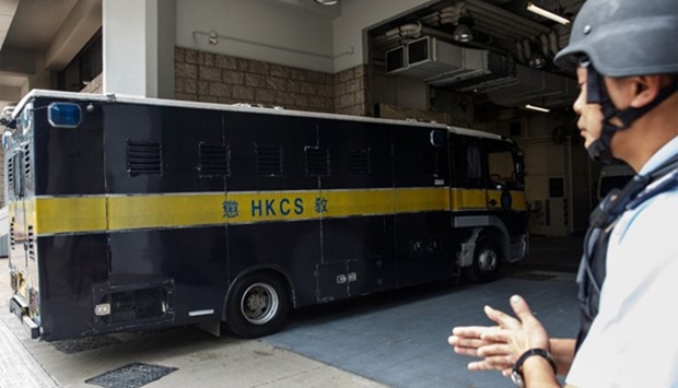 A policeman stands guard as a prison van transporting British banker Rurik Jutting