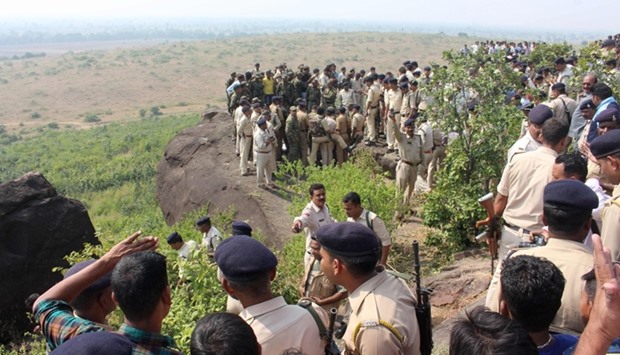 Indian police and bystanders gather at the site where eight SIMI activists, who escaped from Central Jail in Bhopal, were killed by Special Task Force police at the hillocks of Acharpura village, near the capital Bhopal