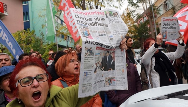 Participants hold the latest copy of Turkish newspaper Cumhuriyet outside the headquarters in Ankara, during a protest against the detention of the newspaper's editor-in-chief and a dozen journalists and executives.