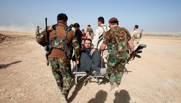 Kurdish Peshmerga fighters carry a wheelchair-bound man, Abbas Ali, 42, after he escaped with his wife and four children from the Islamic State-controlled village of Abu Jarboa, Iraq