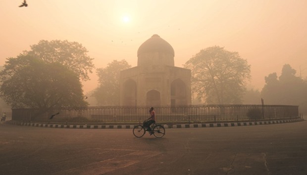 A cyclist rides along a street as smog envelops a monument in New Delhi yesterday.