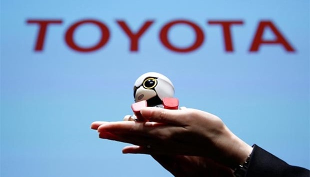 A staff member holds Toyota Motor Corp\'s Kirobo Mini in her hands as she poses with the robot in Tokyo.